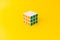 3x3 Rubik's cube isolated on yellow background. 3 by 3 Logic toy solved with white on top.