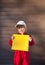 4- 5 year old boy in red mechanic uniform holds yellow box in front of him