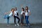 4 beautiful girls in ordinary clothes posing on camera against a concrete gray wall, smiling in an excellent mood and
