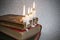 4 burning candles with dripping wax on vintage hard cover books