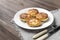 4 cheesecakes on a plate ,4 cheese fritters on a white plate, fork, knife on a napkin on a wooden background