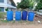 4 large blue plastic bins placed on an outdoor area, a spot for sorting out litter.