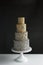 4 tier wedding cake with silver floral accents. On white table with with dark grey background and copy space.