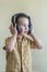 A 4 year boy in a shirt attentively listens to music in big black headphones. Little boy listening to music in big black headphone