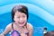 4-year-old Asian girl is crying in blue pool while playing in water and there is accident in water play activities at home.