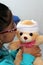 4-year-old brunette Latina girl with glasses represents mistreatment and physical abuse in her teddy bear with bandages on her hea
