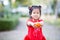 4 year old child girl is handing orange in her front. Fruit that symbolizes good luck and wealth. Chinese New Year Festival.