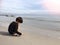 4 years old Asian boy sand writing on beach with sea and sky