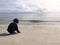 4 years old Asian boy sand writing on beach with sea and sky ba