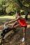 42 years old Brazilian woman doing stretching leaning on a wooden bench in a public square side view