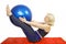 A 48-year-old woman performs an exercise from a Pilates course compresses kicking the ball the fitball and raises them