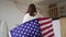 4k 10 bit. A patriotic woman with a US national flag celebrates, backview. Independence Day