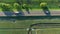 4K aerial footage of cars vehicles buses riding on a road between green fields in the sun rise