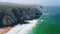 4K Aerial reveling view of Atlantic ocean coastline. White waves rolling towards rocky cliffs near Praia Grande beach