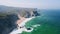 4K Aerial reveling view of Atlantic ocean coastline. White waves rolling towards rocky cliffs near Praia Grande beach