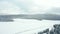 4k Aerial view flying over trees and frozen lake surrounded by snowy forest