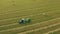 4K Aerial View Tractor Collects Dry Grass In Straw Bales In Wheat Field. Special Agricultural Equipment. Hay Bales, Hay