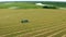 4K Aerial View Tractor Collects Dry Grass In Straw Bales In Wheat Field. Special Agricultural Equipment. Hay Bales, Hay