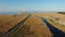 4K. Aerial view with turning wind turbines, blue river, fields, and road near the sea
