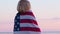 4k.Back view woman in summer clothes with national USA flag outdoors ocean sunset - American flag, country, patriotism