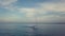 4k backwards dolly aerial of sailing boat through blue seas sunset cloudscape