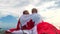 4k. Blonde boy and girl sitiing with national Canada flag outdoors over blue sky at summer - Canada day, country