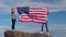 4k. Blonde boy and girl waving national USA flag outdoors over blue sky at summer - american flag, country, patriotism