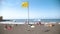 4k blurred out of focus video of people relaxing on volcanic black sand ocean beach. Yellow flag fluttering on sea