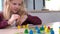 4k Board game and kids leisure concept - little blonde girl playing wood chips people figure in children table top game