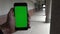 4K caucasian man show the Green Screen phone in aisle with columns