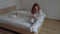 4K CINEMAGRAPH ginger girl sitting in bed and looking at mobile phone