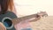 4K. close up of long hair woman playing acoustic guitar at the beach with gentle wind during sunset time, feeling relax