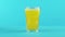 4K close-up shot of fruit fizzy orange cold beverage drink pooring into faceted glass on colored blue background in