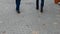 4K Close up shot of two pairs of feet walking along paving stone blocks.