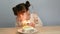 4k. Cute girl with smiley face with cake. Blow candle for birthday celebration party at home with family.