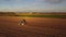 4k drone footage farmer driving tractor deep plowing land at sunset