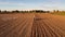 4k drone footage farmer driving tractor deep plowing land at sunset