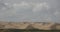 4k far away desert sand dunes under rolling cloud.