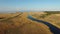 4K. Flight over blue river and fields towards wind turbines near the sea, aerial view at sunset