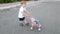 4k footage of adorable toddler boy walking on street with toy stroller for doll. Boy playing with toys for girls. Active