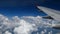 4K footage airplane flight. wing of an airplane flying above the white clouds and blue sky. beautiful aerial view from the window