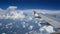 4K footage airplane flight. wing of an airplane flying above the white clouds and blue sky. beautiful aerial view from the window