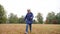 4k footage of cheerful smiling and laughing boy running on dry grass on the field at cold autumn day