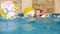 4k footage of happy smiling little boy playing with inflatable colorful beach balls at swimming pool