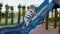 4k footage of little toddler boy trying to climb on high slide at playground