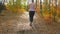 4K footage of slim woman running in autumn forest at sunsetRear view of young woman jogging in forest at sunny morning