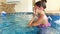 4k footage of teenage smiling girl wearing goggles diving and swimming under water at indoor swimming pool in gym