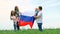4k. Happy family mother father and two kids girl and little boy waving national Russia flag outdoors green grass blue