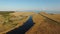 4K. High flight over blue river and fields towards wind turbines and the sea, aerial view at sunset.