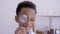 4K, little Asian boy pays attention to a magnifying glass with a happy smile on his eye socket in his elementary school`s white